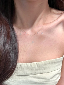 Close-up of gold tassel necklace with zircon teardrop charms on a female model