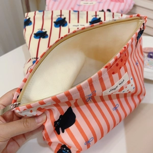 Détail d'une trousse à maquillage en toile rayée rose avec imprimé chat et fermeture