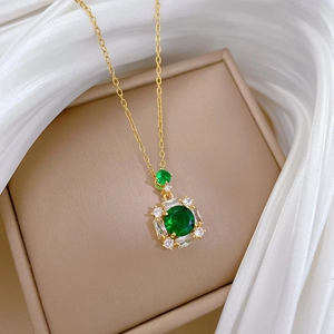 Detailed macro view of square emerald pendant with small crystals on a silk fabric