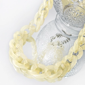 Close-up of a creamy yellow chunky acrylic resin chain wrapped around a glass bottle