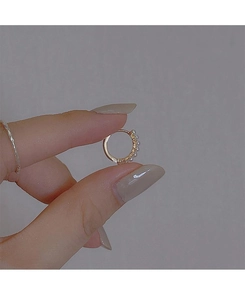 Close-up of small golden hoop earrings with micro pearls held by hand to show size