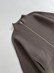 Detail of a brown mock neck knit cardigan featuring front patch pockets and silver zipper