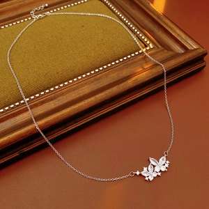 Gros plan du collier papillon en argent avec zircons sur fond de bois vintage