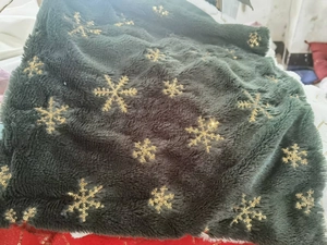 Macro detail of dark green plush fabric with golden sequin snowflake embroidery