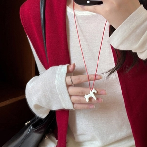 Close-up of a cute white enamel pony pendant necklace with a stylish red cord