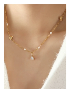 Dettaglio ravvicinato di una collana dorata con stella e zircone su maglione bianco