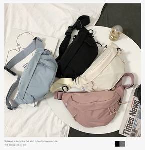 Flat lay of colorful nylon chest bags in black, blue, beige, and pink with adjustable straps