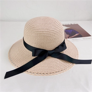 Detailed top view of a beige straw sun hat with black ribbon bow and lace edge trim