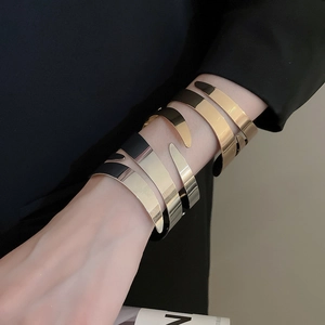 Polished metallic double-layer open cuff bracelets in gold and silver on a model wrist