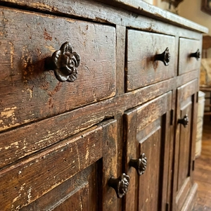 Vintage rose iron cabinet knob on distressed dark wood drawer in rustic industrial style