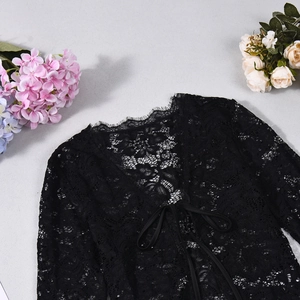 Detailed flat lay of black lace tie-front cardigan with intricate floral patterns