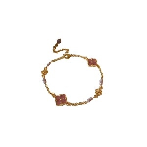 Vintage gold-plated bracelet with pink clover charms and delicate beads on a white surface