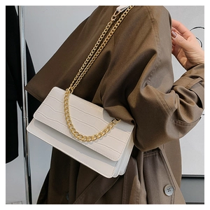 Détail de la texture crocodile blanche et de la chaîne dorée sur le sac à bandoulière