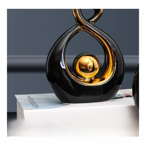 Detail of modern ceramic sculpture with black glaze and a golden sphere on minimalist books