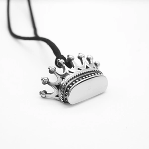 Detailed close-up of a silver crown pendant on a black cord necklace for men and women