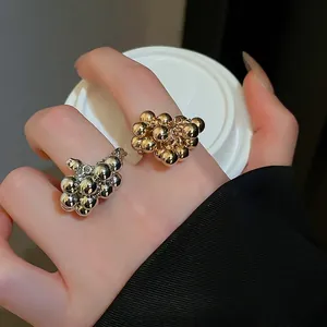 Irregular spherical gold and silver open rings with a glossy berry-like cluster design