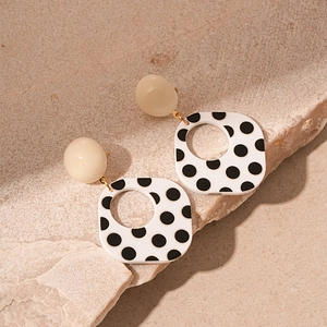 Close-up of vintage black and white polka dot acrylic square earrings on a stone surface