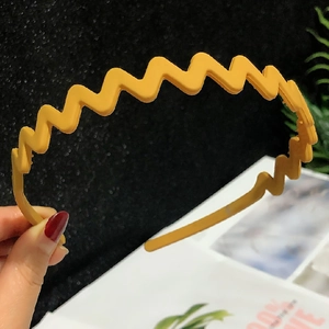 Close-up of yellow wavy plastic headband showing flexible side texture and ergonomic design