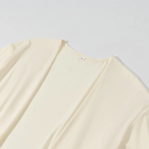 Dettaglio dello scollo a V e dell'etichetta taglia S su un cardigan in maglia color crema