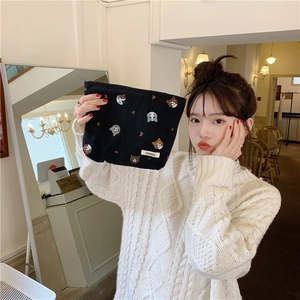 Close-up of black canvas pouch with embroidered cat patterns held by a model