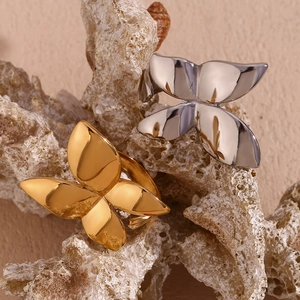 Close-up of gold and silver butterfly rings on coral with a polished metallic finish