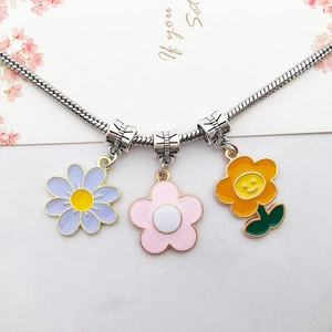 Silver snake chain necklace with three colorful enamel flower pendants on white background