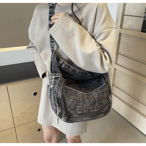 Détail du sac bandoulière en denim gris foncé vintage avec bords usés et poches