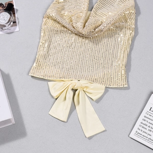 Détail d'un haut à paillettes crème avec un grand nœud en satin à l'ourlet chic