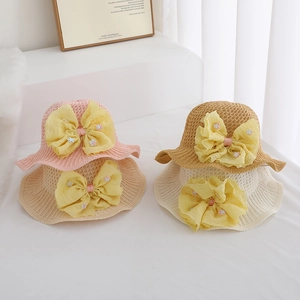 Close-up detail of four colorful children's straw hats featuring large yellow daisy floral bows.