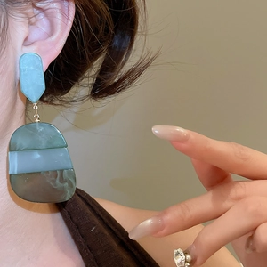 Close-up of geometric acetate oval drop earrings with marble texture on model