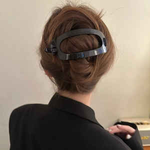 Pince à cheveux ovale noire minimaliste portée sur un chignon élégant pour femmes