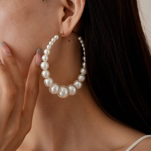 Close-up of elegant gradient pearl hoop earrings on a model showing the large circular design