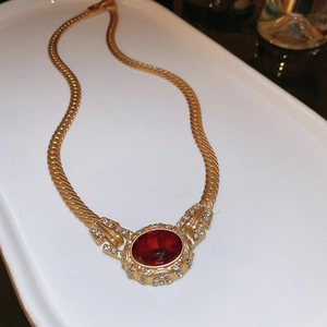 Detailed macro view of vintage gold necklace with oval red gemstone and crystal accents