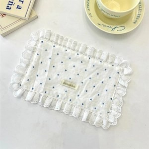 Detail of white cotton placemat with blue heart prints and delicate lace ruffle edges