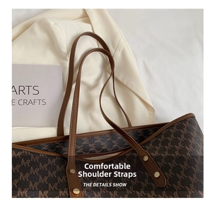 Dettaglio della borsa tote in tela monogram con manici in pelle marrone e rivetti dorati