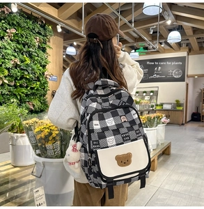 Close-up of checkerboard backpack with teddy bear patch and plush rabbit charm