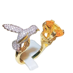 Exquisite hummingbird ring featuring an oval orange gemstone and pavé crystal birds