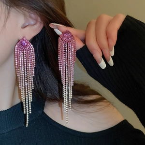 Close-up of sparkling pink gradient rhinestone fringe earrings worn by a female model