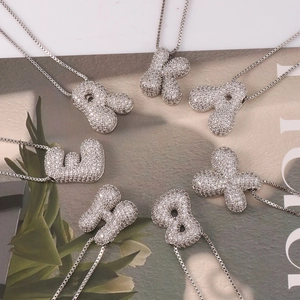 Close-up of silver-tone zircon-paved alphabet pendants on delicate chain necklaces