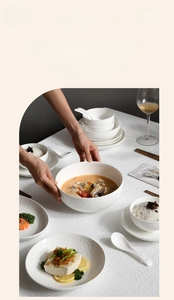 Detailed view of white embossed ceramic tableware set on woven tablecloth with soft lighting