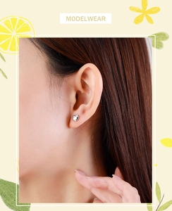 Close-up of minimalist silver apple stud earrings worn on ear with fresh aesthetic