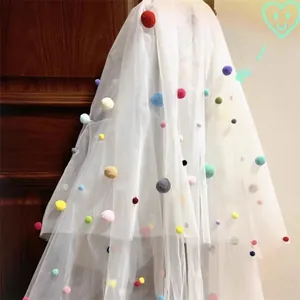 Detail of white mesh veil fabric with colorful pom-pom balls for party photo props