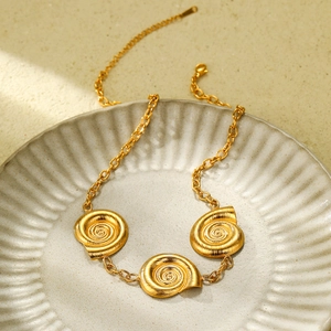 Close-up of golden snail shell pendant with spiral texture and brushed metal finish