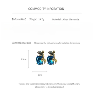 Detail view of vintage style blue crystal earrings with gold fish and diamond accents