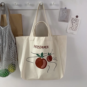 Detail of off-white canvas tote with PERSIMMON print hanging in a minimalist home setting