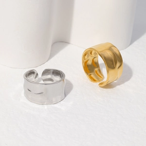 Detail of minimalist wide open rings with irregular hammered lava texture in gold and silver