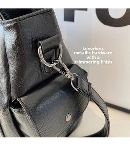 Detail of silver metallic lobster clasp and D-ring on black pebbled leather tote bag