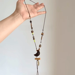 Detail of bohemian beaded necklace with moon pendant and resin tassels on a long cord