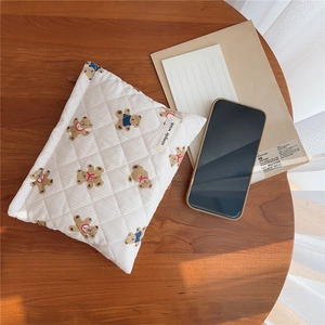 Detailed view of quilted makeup bag with bear print on a warm wooden desktop