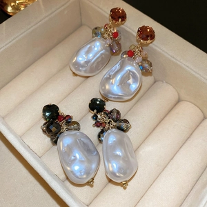 Detailed close-up of Baroque pearl earrings with crystal studs in a velvet jewelry box